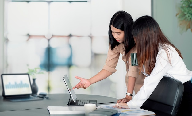 Twee jonge Aziatische vrouwen bespreken over businessplan op kantoor.