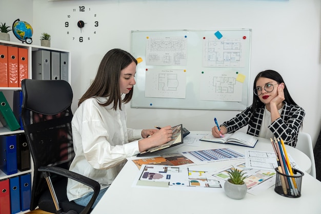 Twee jonge blanke vrouwelijke architecten werken samen om het ontwerphuisplan op kantoor uit te geven