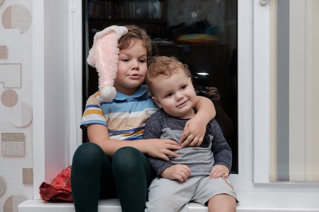 Foto twee jonge broertjes zitten op de vensterbank