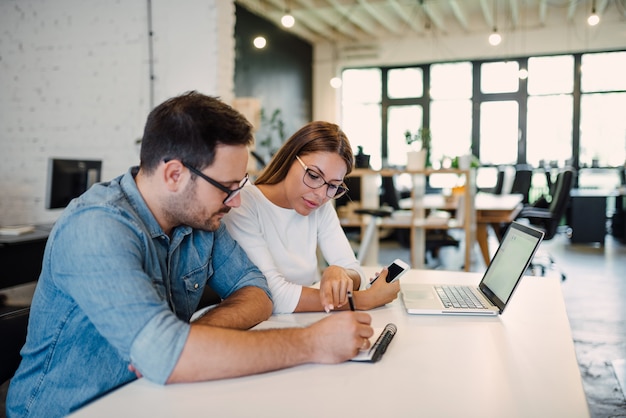 Twee jonge collega&#39;s die in modern open-ruimtekantoor werken.