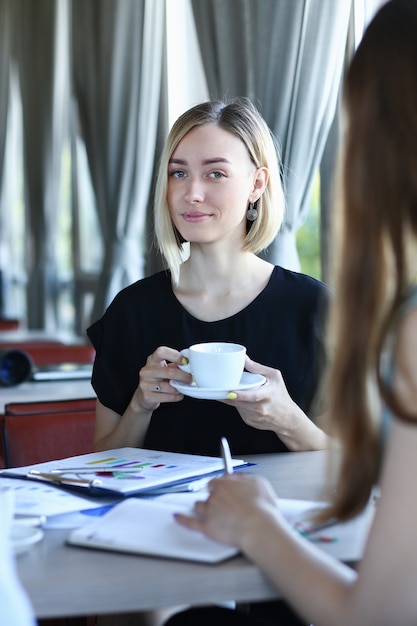 Twee jonge dame praten zitten aan tafel in café