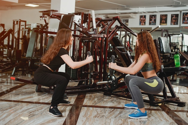 twee jonge en atletische meisjes houden zich bezig met sporten in de sportschool