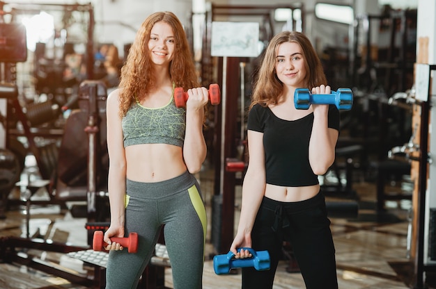 twee jonge en atletische meisjes houden zich bezig met sporten in de sportschool