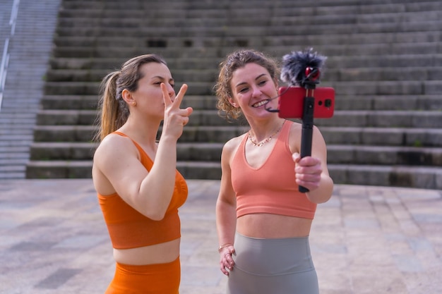 Twee jonge fitnessmeisjes in een stadspark nemen een online les op voor studenten