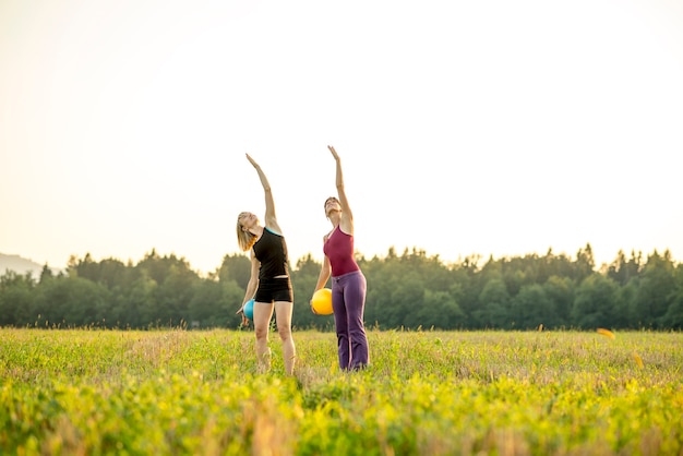 Twee jonge fitte vrouwen die pilates doen en één arm in de lucht tillen