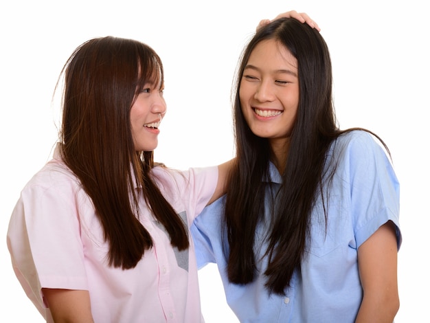 Twee jonge gelukkige Aziatische tienermeisjes glimlachen