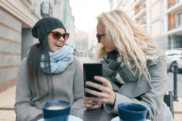 Twee jonge glimlachende modieuze vrouwen die pret hebben