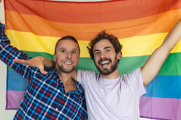 Twee jonge homoseksuele geliefden die elkaar liefdevol aankijken Twee jonge mannelijke geliefden die samen staan tegen een trotsvlag Aanhankelijk jong homopaar die een romantisch moment samen delen