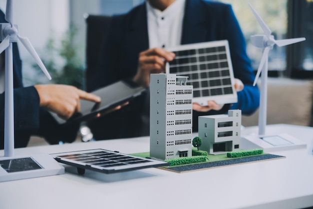 Twee jonge ingenieurs, deskundigen op het gebied van de installatie van zonnepanelen, vergaderden en bespraken de werkzaamheden met betrekking tot de planning van het installeren van zonne-photovoltaïsche panelen op het dak van de kantoorkamer met een fabrieksbouwplan.