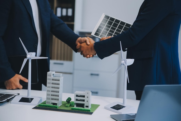 Twee jonge ingenieurs, deskundigen op het gebied van de installatie van zonnepanelen, vergaderden en bespraken de werkzaamheden met betrekking tot de planning van het installeren van zonne-photovoltaïsche panelen op het dak van de kantoorkamer met een fabrieksbouwplan.