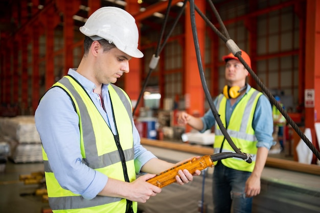 Twee jonge ingenieurs testen en controleren de werking van de semi-gantry kraan