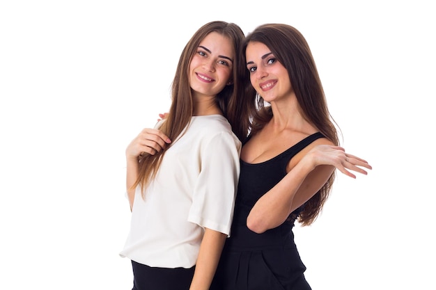 Twee jonge knappe vrouwen in witte en zwarte shirts omarmen op witte achtergrond in studio