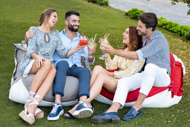 Twee jonge koppels die plezier hebben met een groep vrienden in de buitenlucht die praten tijdens een sociale bijeenkomst van een cocktailparty en een happy hour-concept