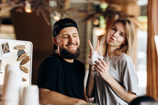 Foto twee jonge lachende people.dressed in casual outfit, naast elkaar staan en glimlachen naar de camera in een gezellige coffeeshop. .