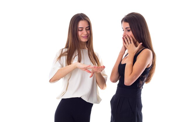 Twee jonge lachende vrouwen in zwarte en witte shirts praten over manicure op witte achtergrond