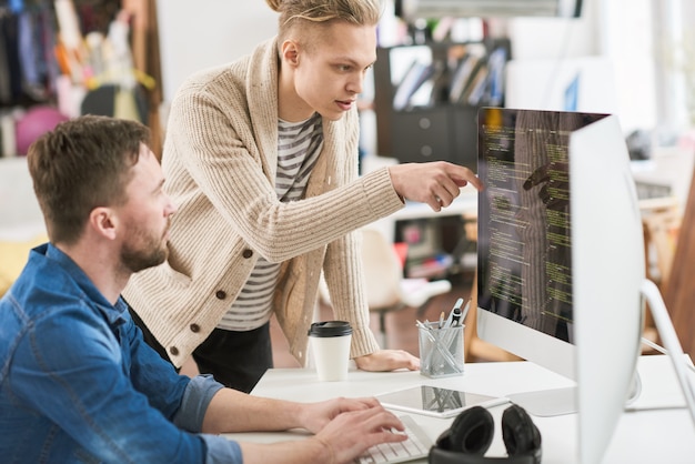 Twee jonge mannen die samenwerken aan programmacode