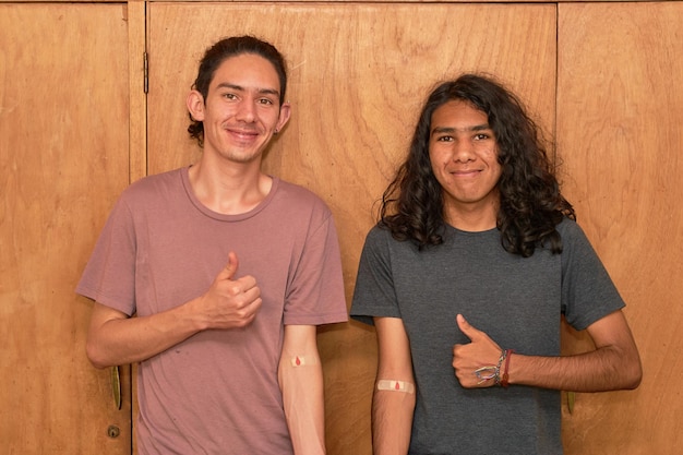 Twee jonge mannen met armen bedekt met een pleister omdat ze bloed hebben gedoneerd