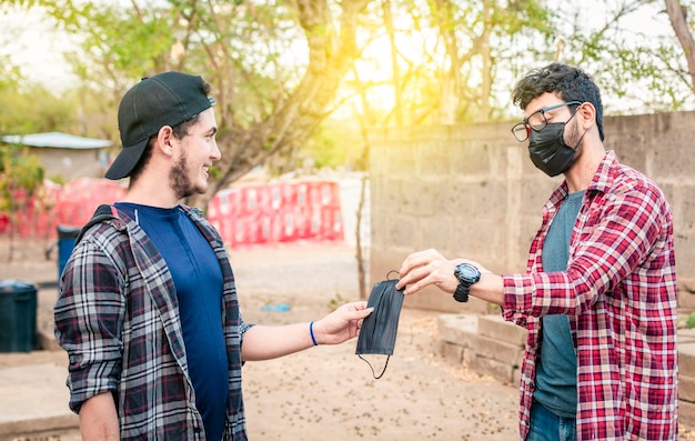 Twee jonge mensen die elkaar een masker geven afbeelding van een jonge man die een masker geeft aan een andere persoon concept van een persoon die een masker aanbiedt