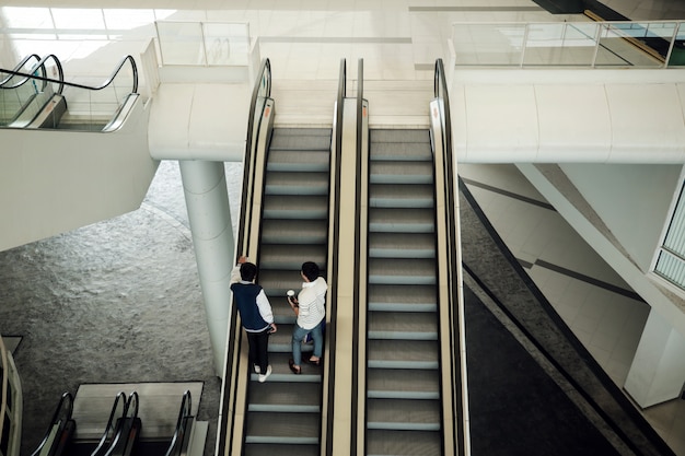 Twee jonge mensen op roltrap aan de moderne universiteit