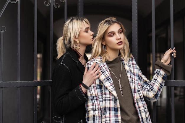 Twee jonge mode-lesbiennes in stijlvolle kleding poseren op straat