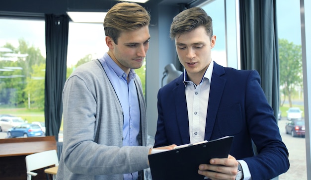 Twee jonge moderne mannen bespreken werk op kantoor.