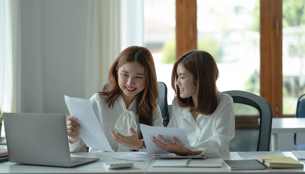 Twee jonge, mooie Aziatische zakenvrouwen in het gesprek die ideeën uitwisselen op het werkxA