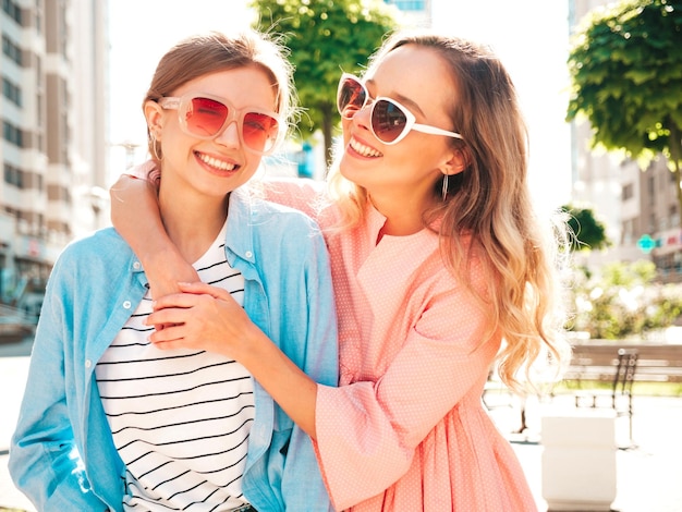 Twee jonge mooie lachende hipster vrouw in trendy zomer kleding en dressSexy zorgeloze vrouwen poseren op de straat achtergrond Positieve pure modellen plezier bij zonsondergang knuffelen en gek worden