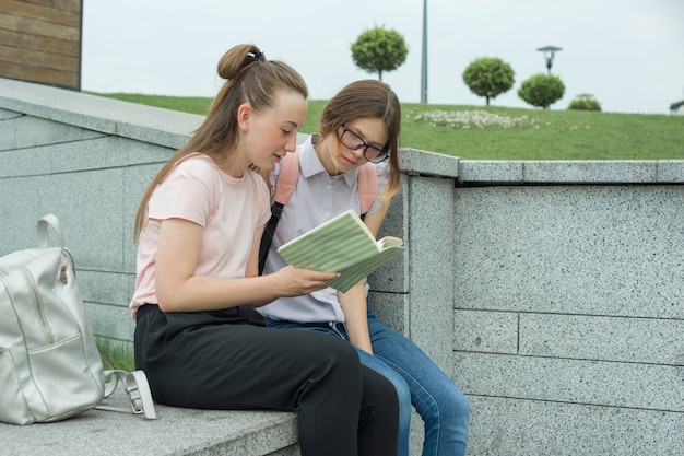 Twee jonge mooie meisjesstudenten met rugzakken, boeken