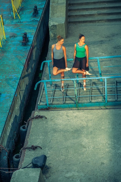 Twee jonge mooie tweelingzus dansen ballet in de stad met ballet kostuum urban sync dance