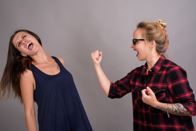 twee jonge mooie vrouw vrienden samen op grijs