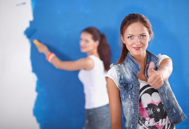 Twee jonge mooie vrouwen die een kleurenpalet houden dat zich dichtbij de muur bevindt Twee jonge mooie vrouwen