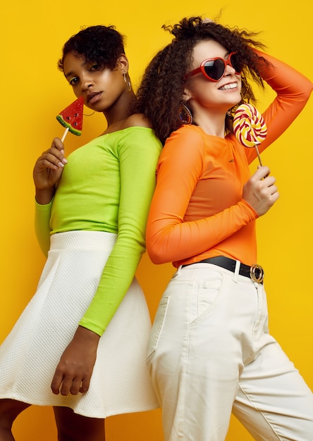 Twee jonge mooie vrouwen in kleurrijke zomerkleren met lollys