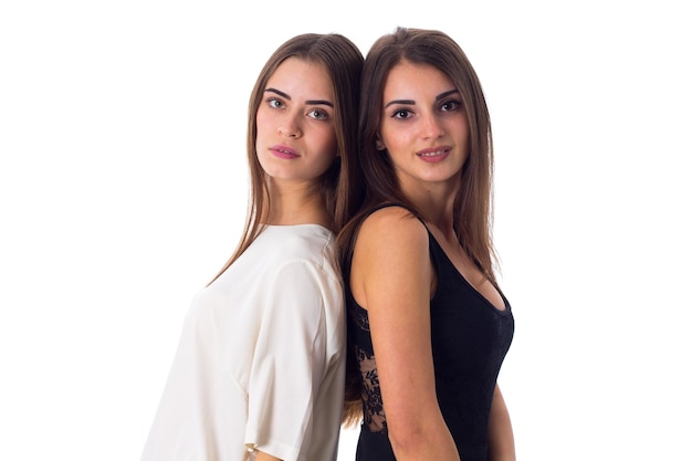 Twee jonge mooie vrouwen in witte en zwarte shirts omarmen op witte achtergrond in studio