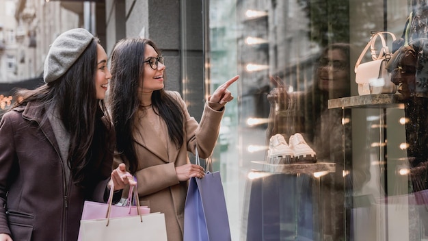 Twee jonge mooie vrouwen winkelen graag terwijl ze met de vinger in de etalage wijzen