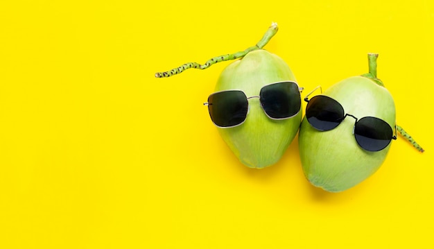 Twee jonge oconut met zonnebril op gele achtergrond. Geniet van het concept van de zomervakantie.
