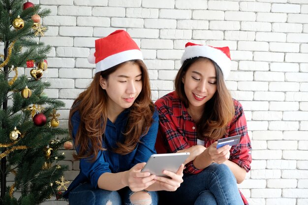 Twee jonge schattige Azië vrouwen houden van de tablet en creditcard tijdens het online winkelen