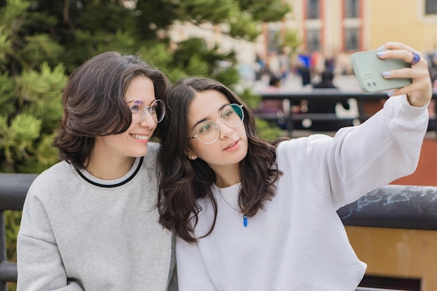 Twee jonge studenten die een selfie maken in het park die genieten en glimlachen.