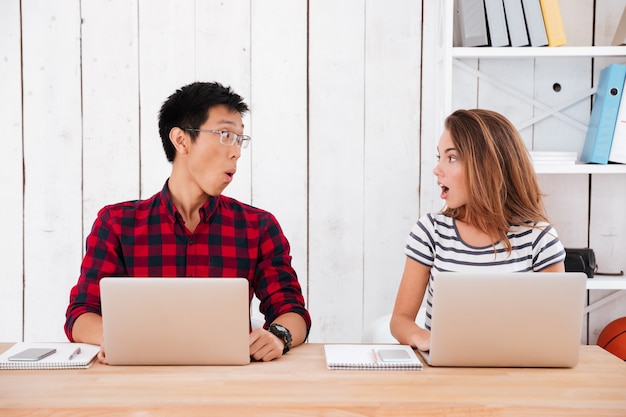 Twee jonge studenten die geschrokken waren van wat er op de laptops in de klas te zien was. Elkaar aankijken