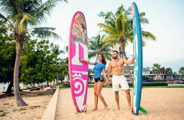 Twee jonge surfers met planken op het strand