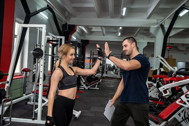 Twee jonge trainers, een man en een vrouw, trainen in de sportschool om de gezondheid van hun lichaam te behouden. Concept van coaches in de sportschool