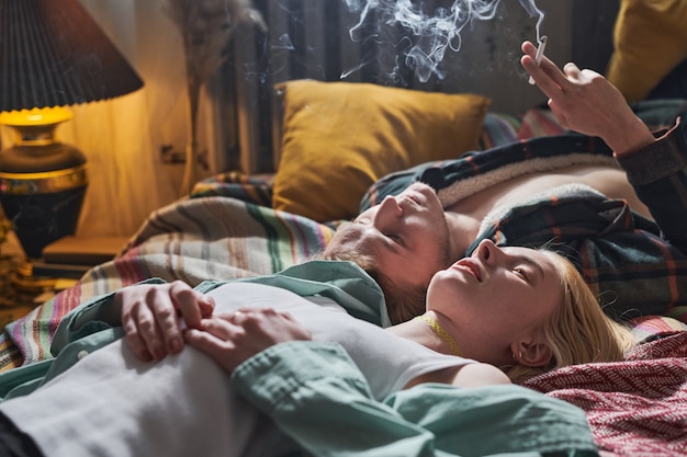 Twee jonge vrienden die op het bed liggen en een sigaret roken en genieten van de stilte in de kamer