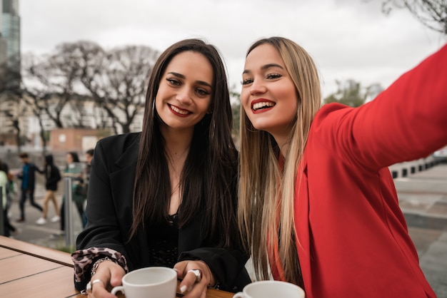 Twee jonge vrienden nemen een selfie samen bij coffeeshop