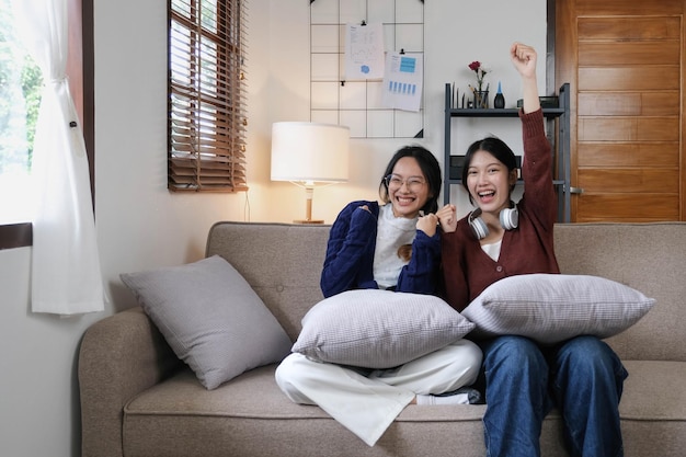 Twee jonge vrouw juichen samen voor sport op tv in een gezellige woonkamer thuis