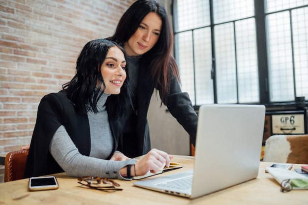 Twee jonge vrouwen binnen met behulp van laptopcomputer