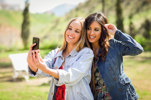 Twee jonge vrouwen die een selfiefoto in stedelijk park nemen