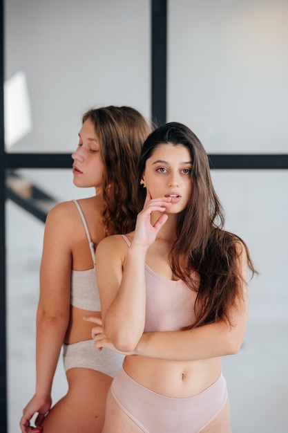 Twee jonge vrouwen die in lingerie staan, kijken zelfverzekerd naar de camera