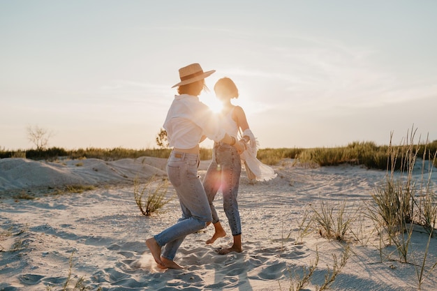 Twee jonge vrouwen die plezier hebben op het zonsondergangstrand