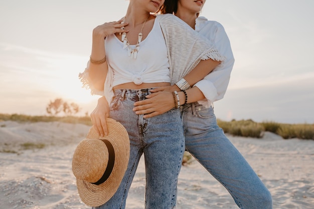 Twee jonge vrouwen die plezier hebben op het zonsondergangstrand