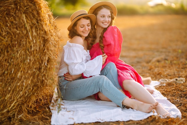 Twee jonge vrouwen die pret hebben dichtbij hooiberg Manierconcept Zomerconcept