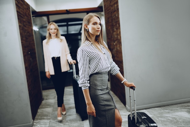 Twee jonge vrouwen in formele kleding die de lobby van het hotel binnengaan